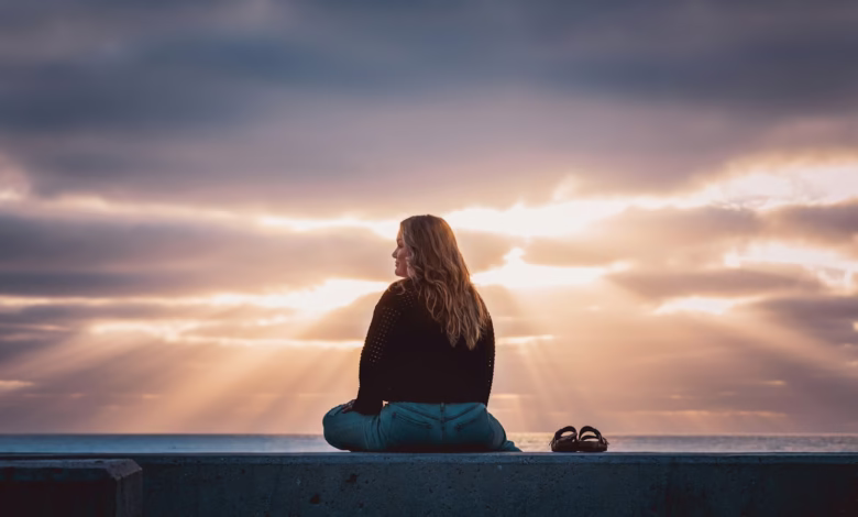 A woman sitting on a wall looking at the sky