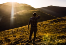 man standing on hill under white sky at daytime
