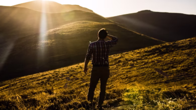 man standing on hill under white sky at daytime