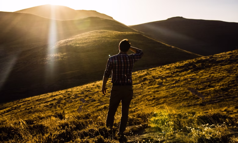 man standing on hill under white sky at daytime