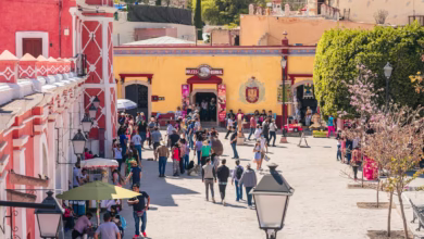 a crowd of people walking down a street next to a yellow building