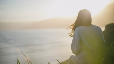woman wearing gray long-sleeved shirt facing the sea