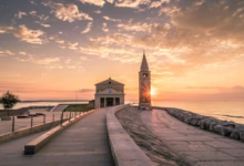 white building beside tower during sunset