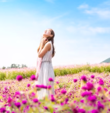 woman wearing white and gray striped sleeveless dress smelling the air standing in the pink flower field at daytime