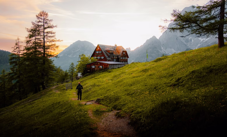 A person hikes towards a house in the mountains.