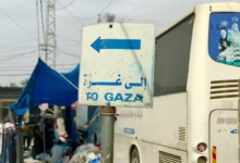a white bus parked next to a blue and white sign