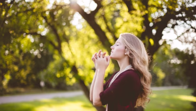 woman praying under tree during daytime