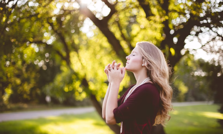 woman praying under tree during daytime