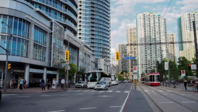 Vibrant street view of Toronto with skyscrapers, traffic, and pedestrians on a sunny day.