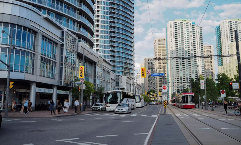 Vibrant street view of Toronto with skyscrapers, traffic, and pedestrians on a sunny day.