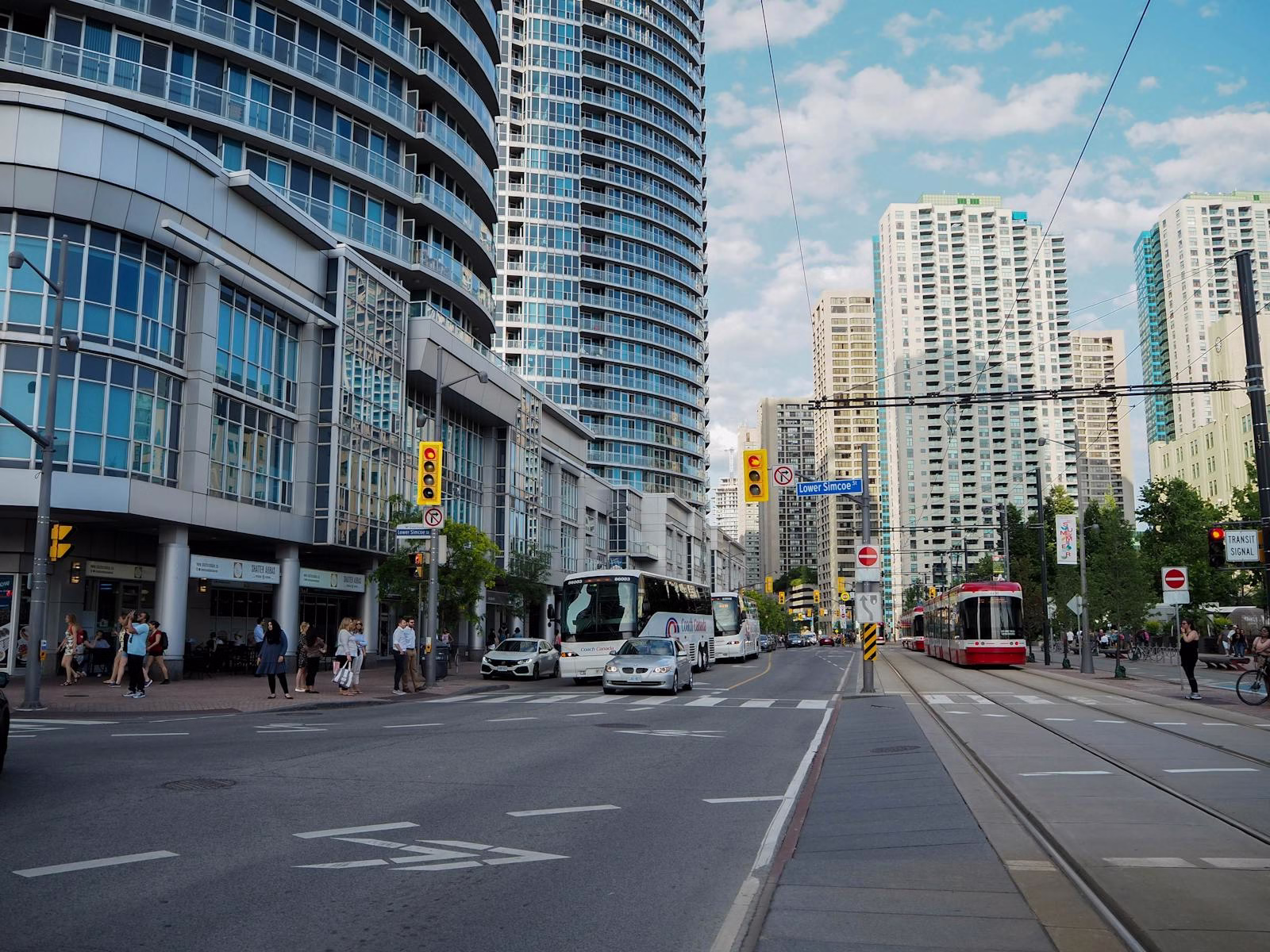 Vibrant street view of Toronto with skyscrapers, traffic, and pedestrians on a sunny day.