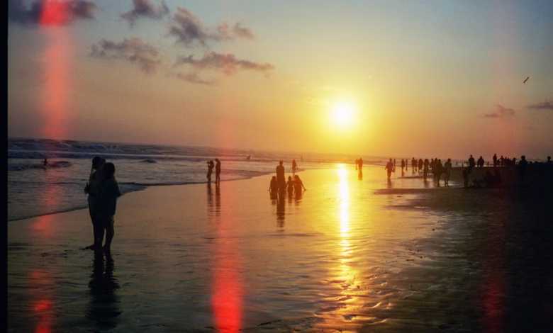 People walking on a beach at sunset
