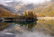 Small house on a hill by a lake with reflections