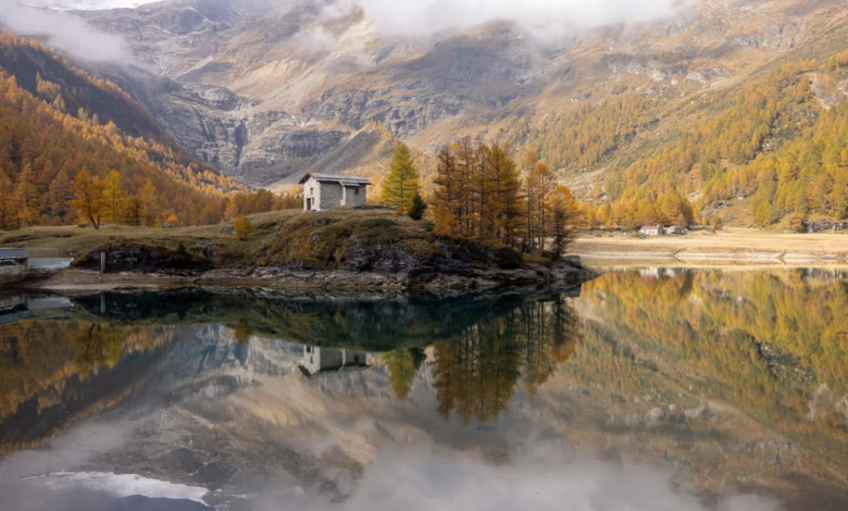 Small house on a hill by a lake with reflections