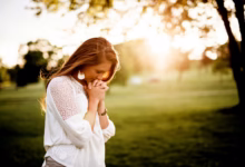 woman praying beside tree