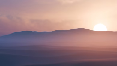 Sun setting behind hazy desert mountains at dusk