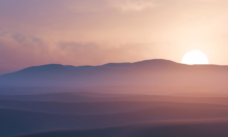 Sun setting behind hazy desert mountains at dusk