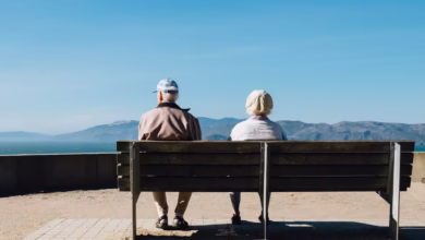 man and woman sitting on bench facing sea