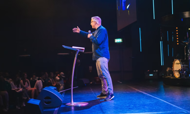 A man standing on top of a stage next to a microphone