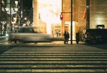 City street at night with blurred car and people.