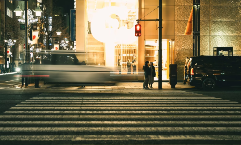 City street at night with blurred car and people.