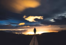 Silhouette of a person against a dramatic twilight sky, overlooking Iceland's scenic landscape.