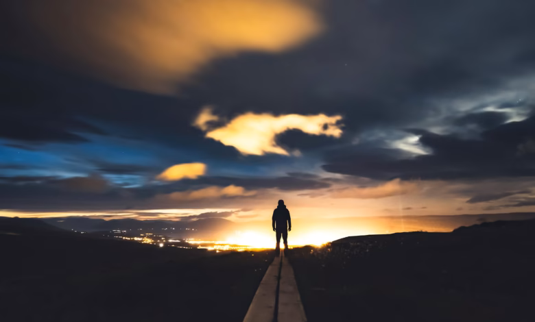 Silhouette of a person against a dramatic twilight sky, overlooking Iceland's scenic landscape.