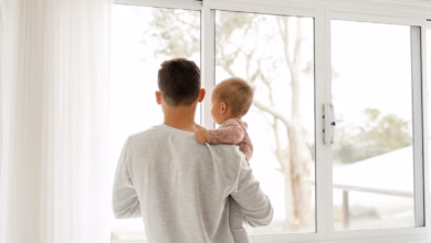 boy in gray sweater standing beside window during daytime