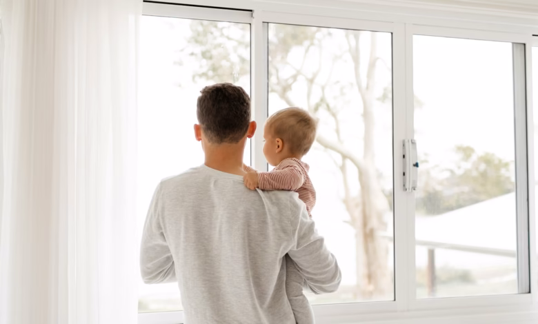boy in gray sweater standing beside window during daytime