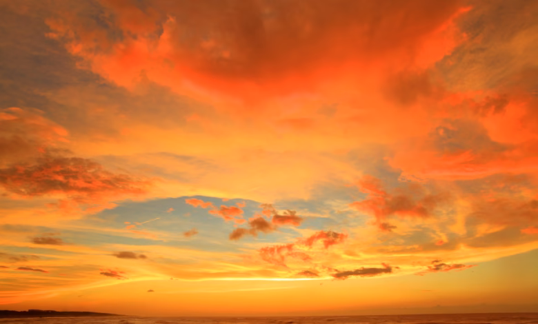silhouette photo of body of water under orange clouds