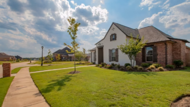 white and brown house near green grass field under white clouds and blue sky during daytime
