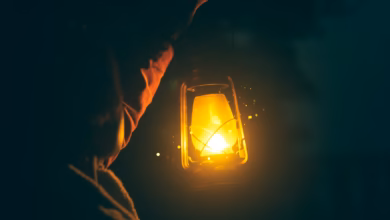 a person holding a lit lantern in the dark