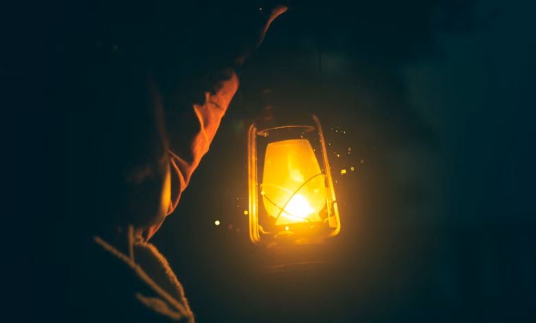 a person holding a lit lantern in the dark