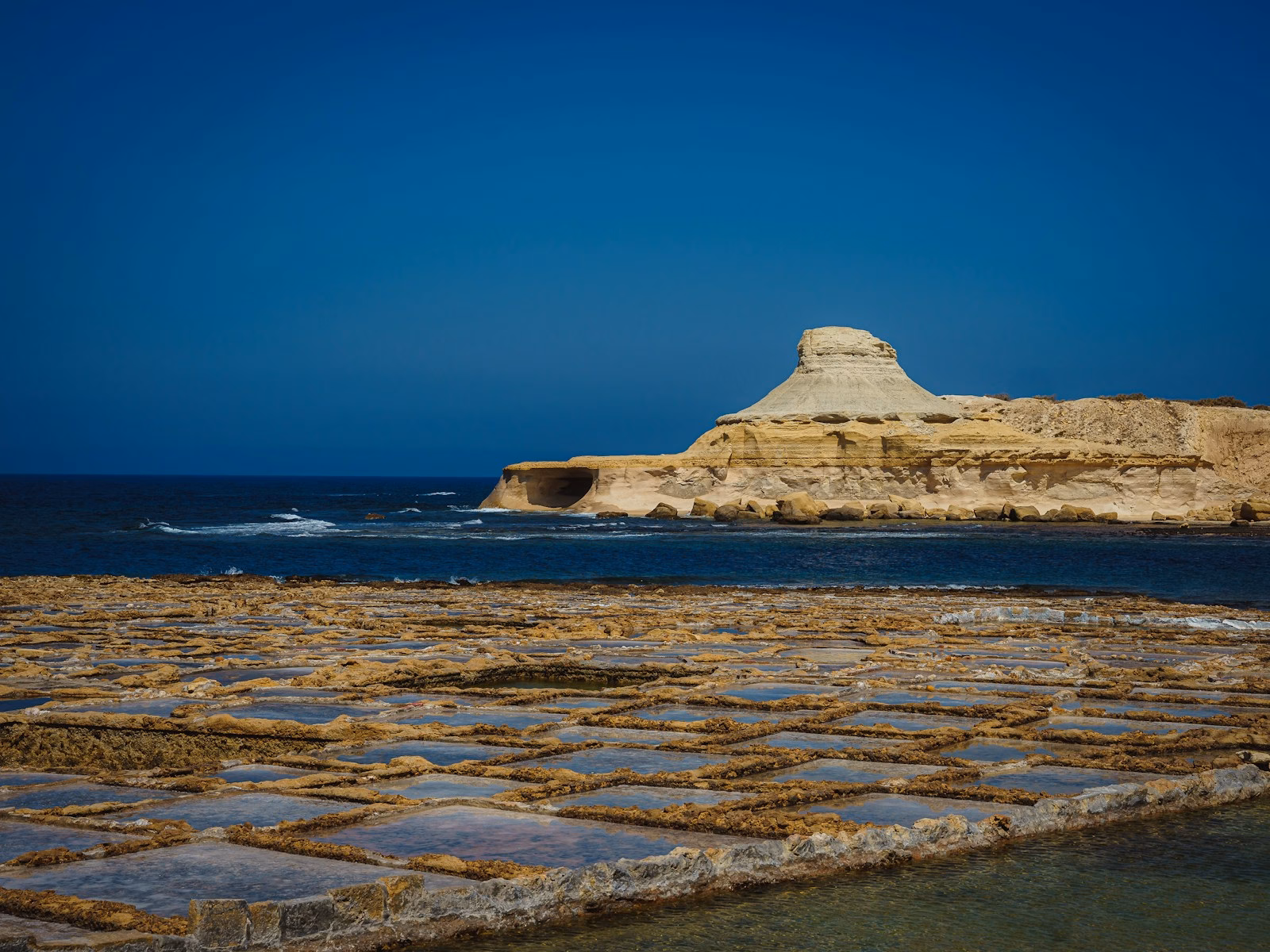 white rock formation on sea under blue sky during daytime